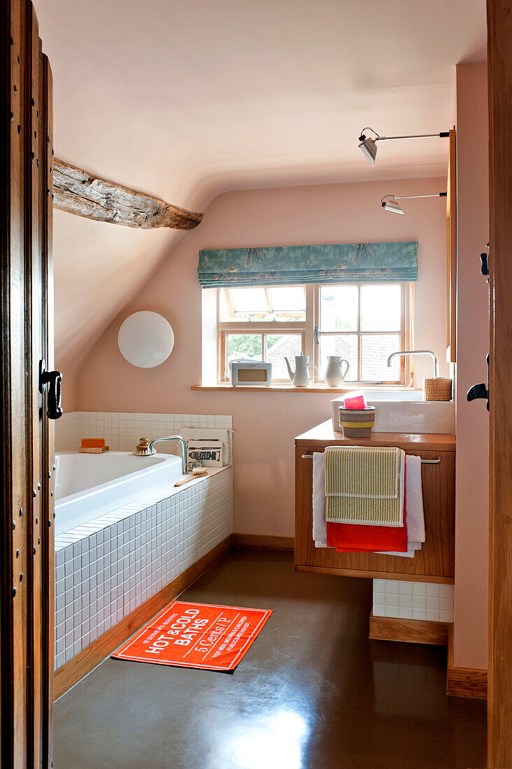 Blick durch die Tür in das pastellrosa Badezimmer eines Hauses in Hertfordshire, England, UK