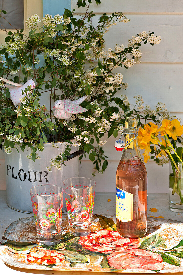 Rosa Limonade und Gläser mit Schnittblumen auf einem Tisch im Sonnenlicht, Haus in Essex, England, Vereinigtes Königreich