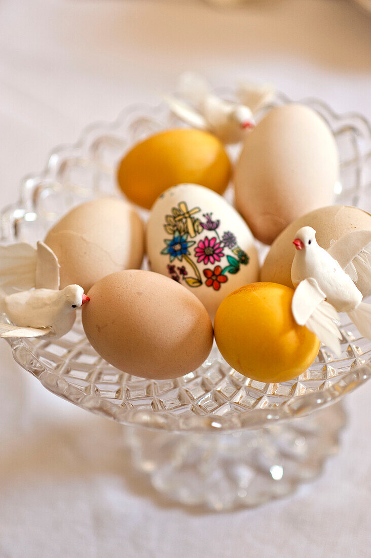 Easter eggs and model birds on glass bowl in Essex home, England, UK