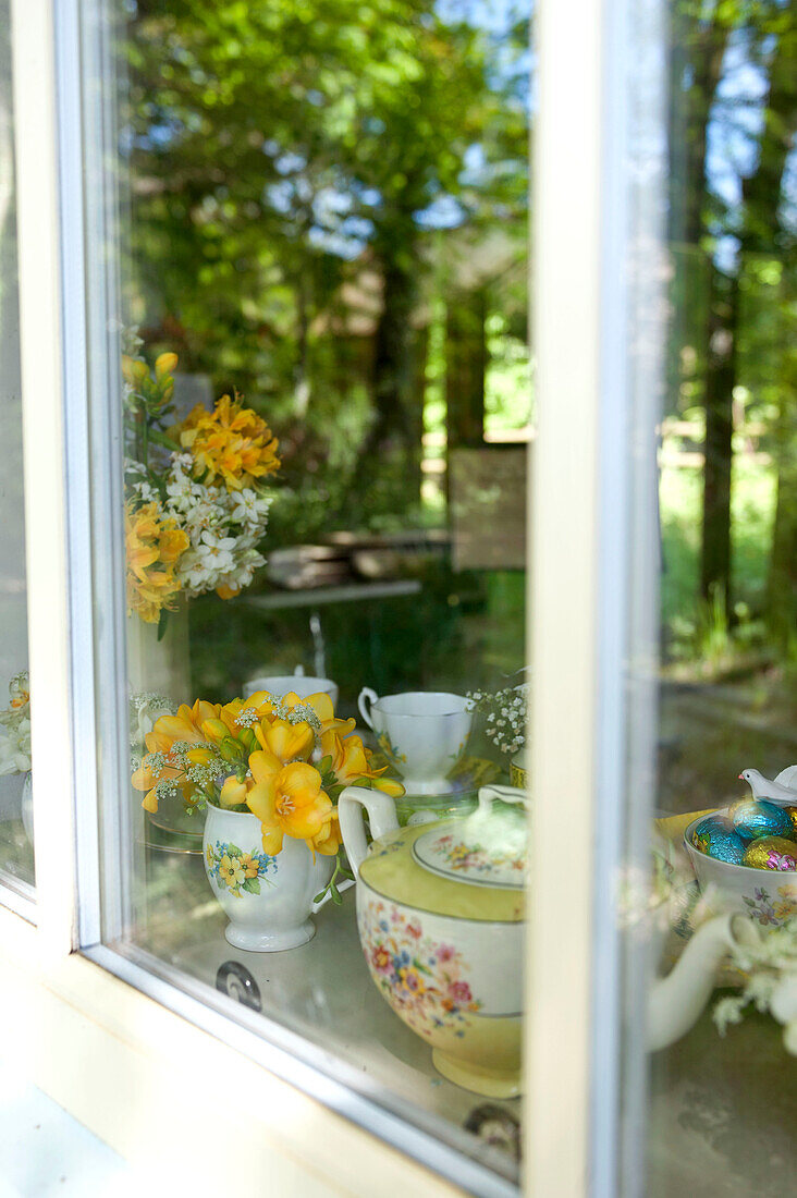 Teekanne und Schnittblumen auf der Fensterbank in einem Haus in Essex, England, UK
