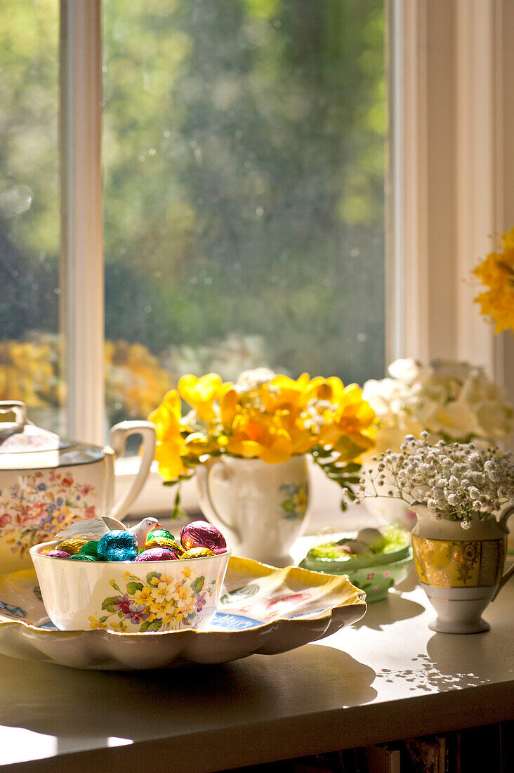 Bowl of Easter eggs with chinaware on sunlit windowsill of Essex home, England, UK