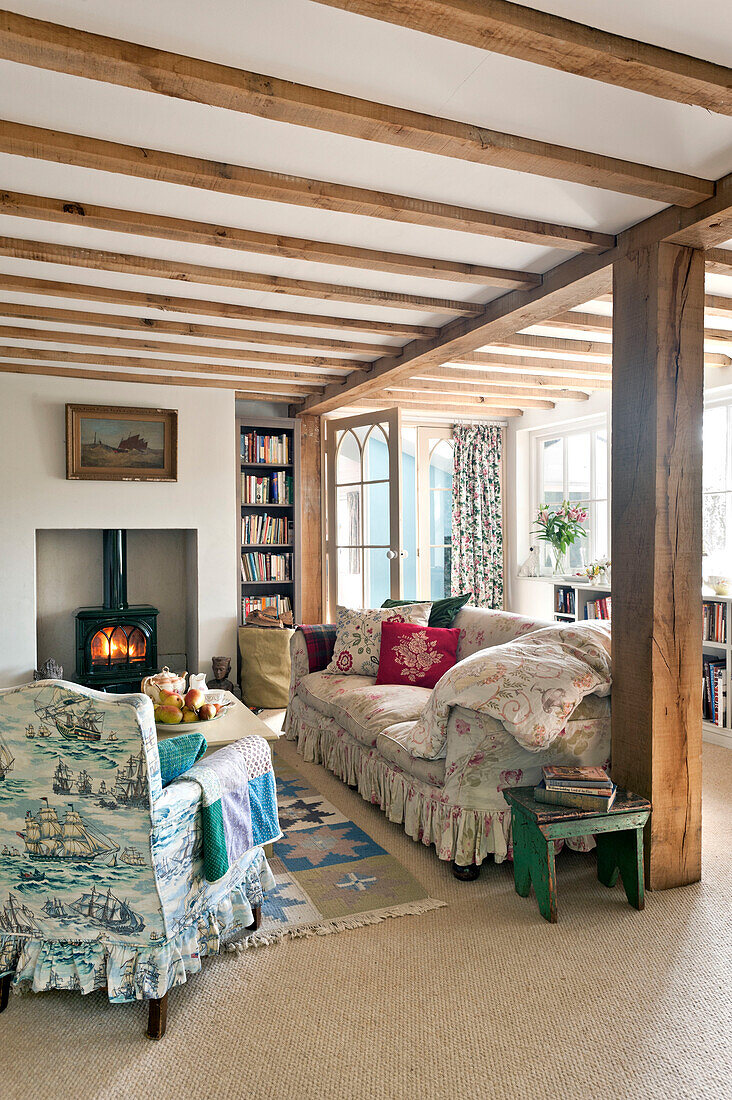 Beamed living room with wood burning stove in Essex home, England, UK