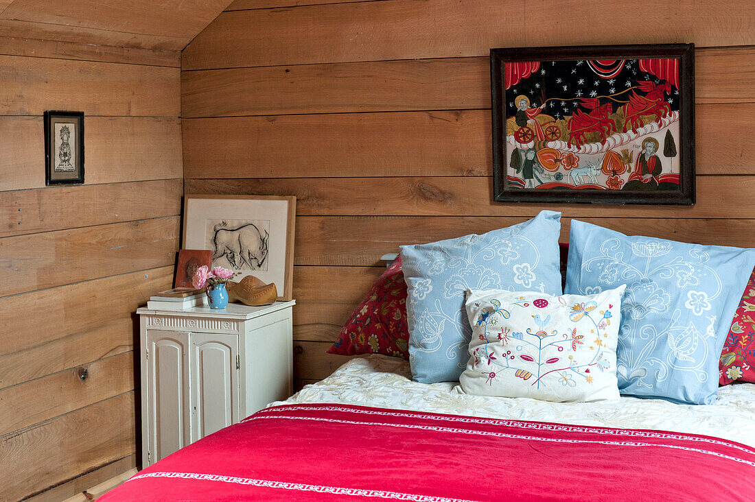 Bestickte Kissen auf dem Bett in einem holzverkleideten Zimmer in einem Haus in Essex, England, UK