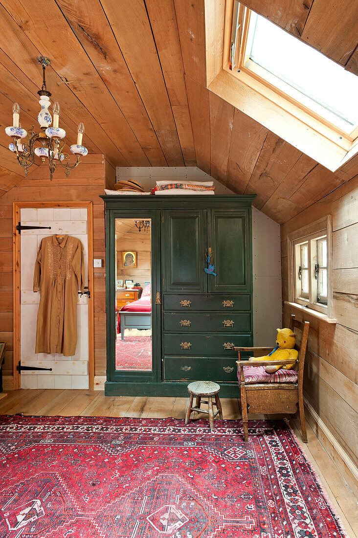 Grüner Kleiderschrank und gemusterter Teppich in einem ausgebauten Dachgeschoss eines Hauses in Essex, England, UK