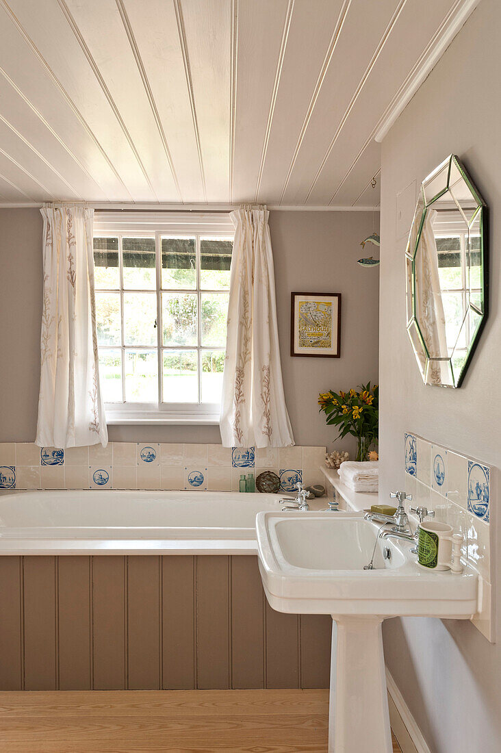 Spiegel über Sockelwaschbecken im weißen Badezimmer eines Hauses in Essex, England, UK