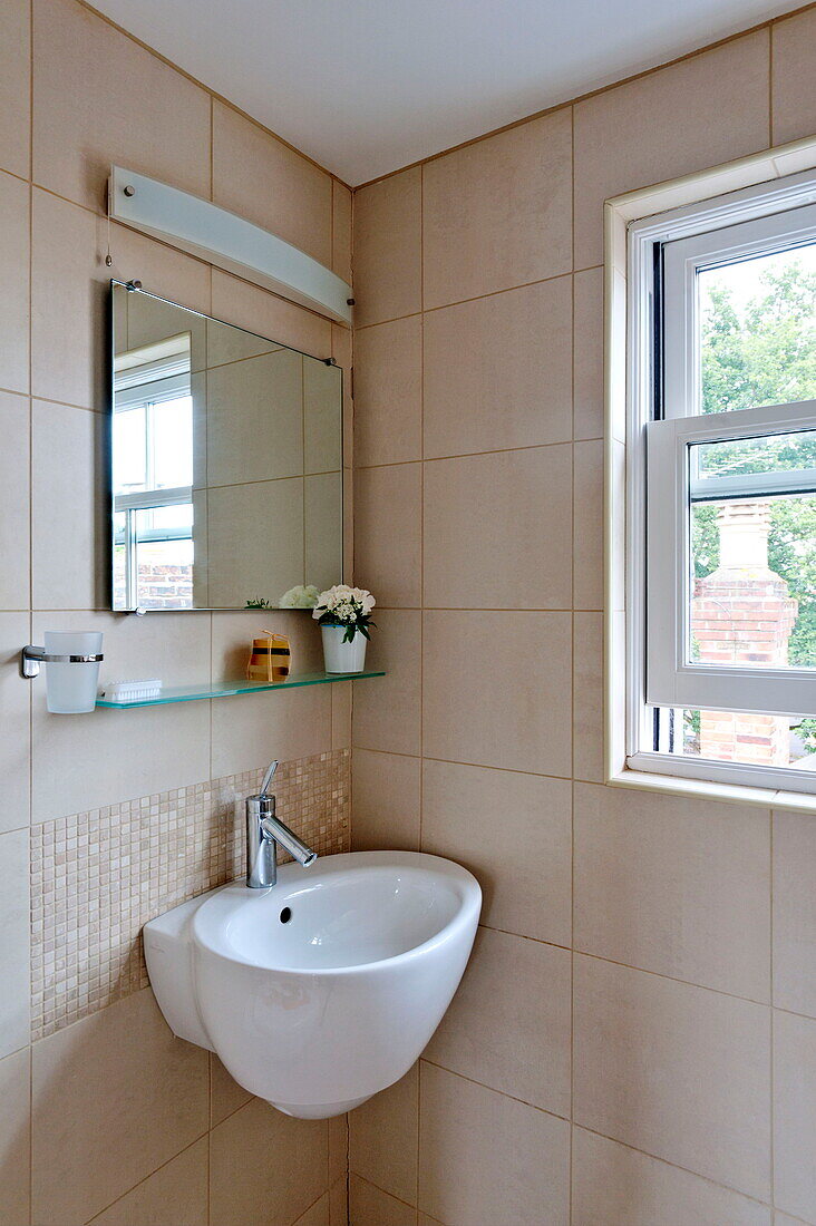 Small basin in tiled cloakroom of Middlesex family home, London, England, UK