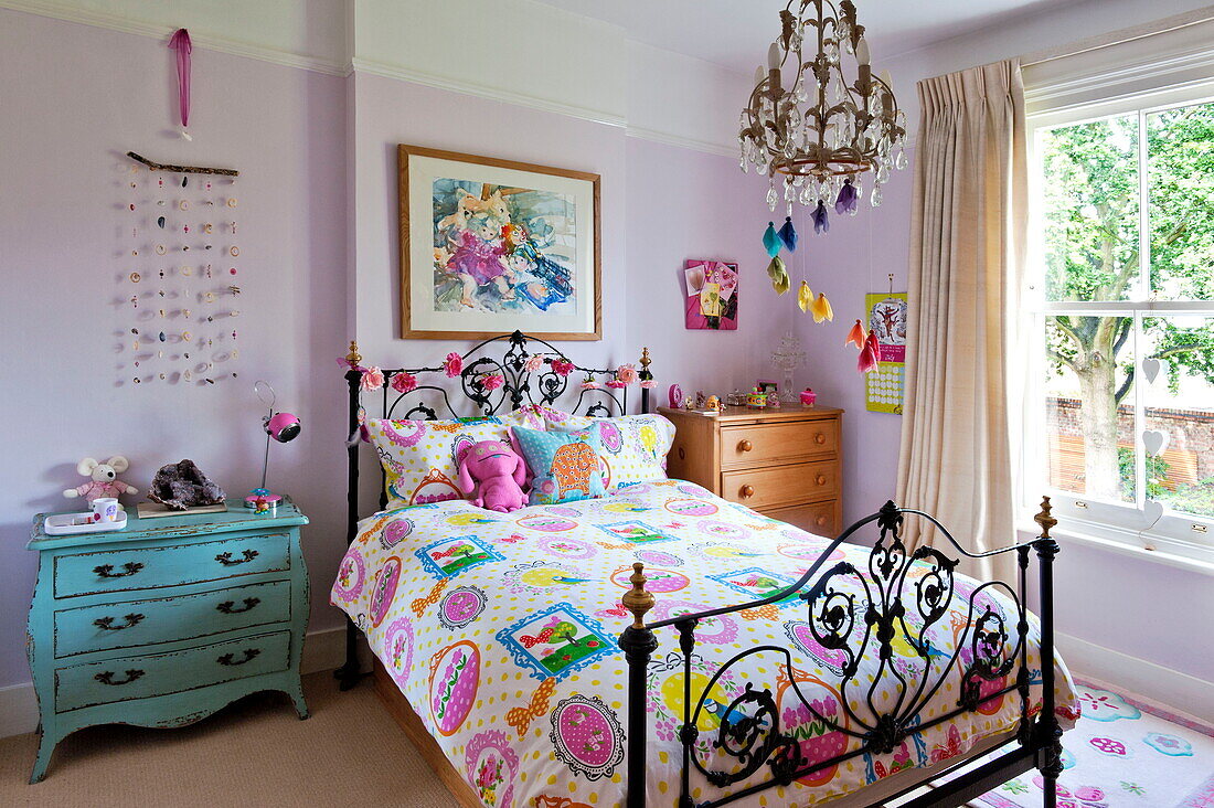 Bunte Bettdecke und Mobile im Schlafzimmer einer Familie in Middlesex, London, England, UK