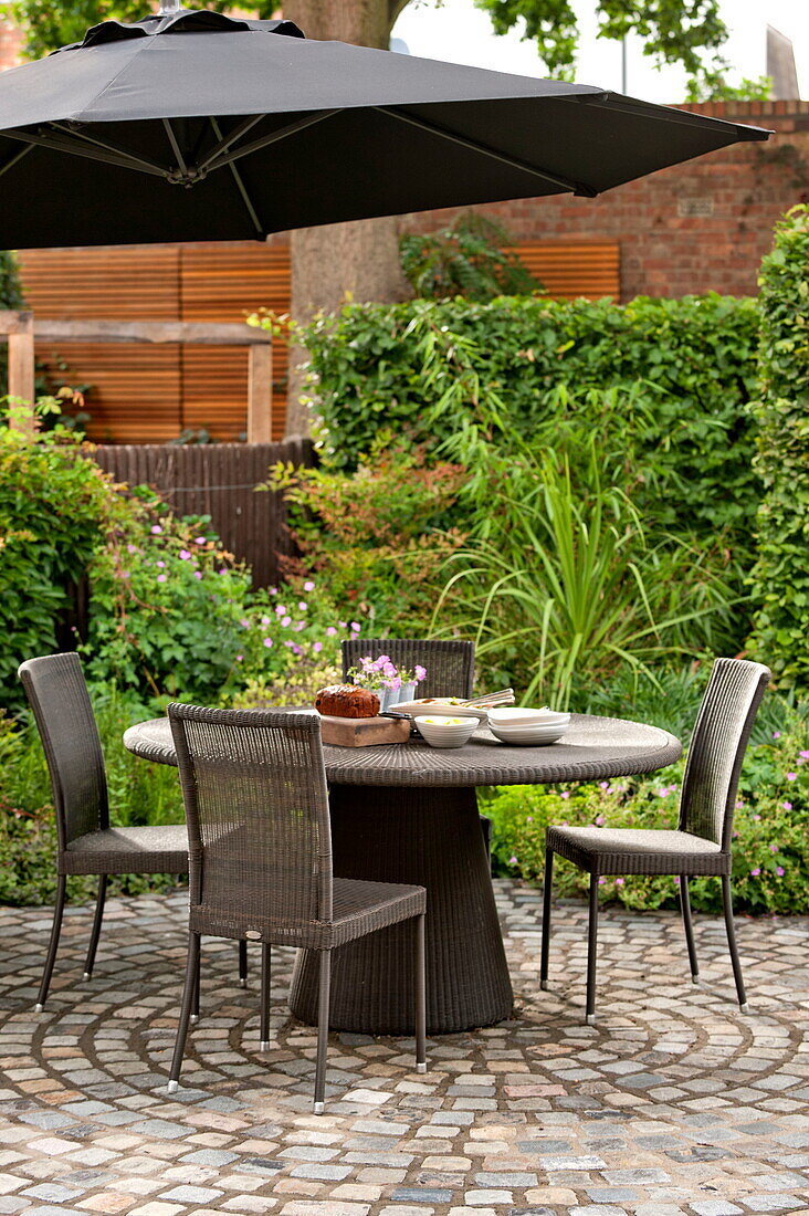 Table and chairs with parasol on patio of Middlesex home, London, England, UK