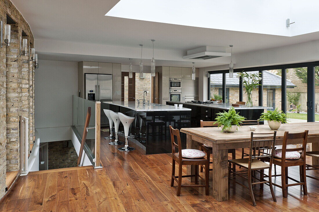 Wooden dining table and chairs in open plan dining room kitchen of London home, England, UK