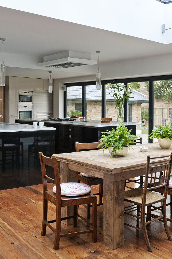 Wooden dining table and chairs in open plan dining room kitchen of London home, England, UK