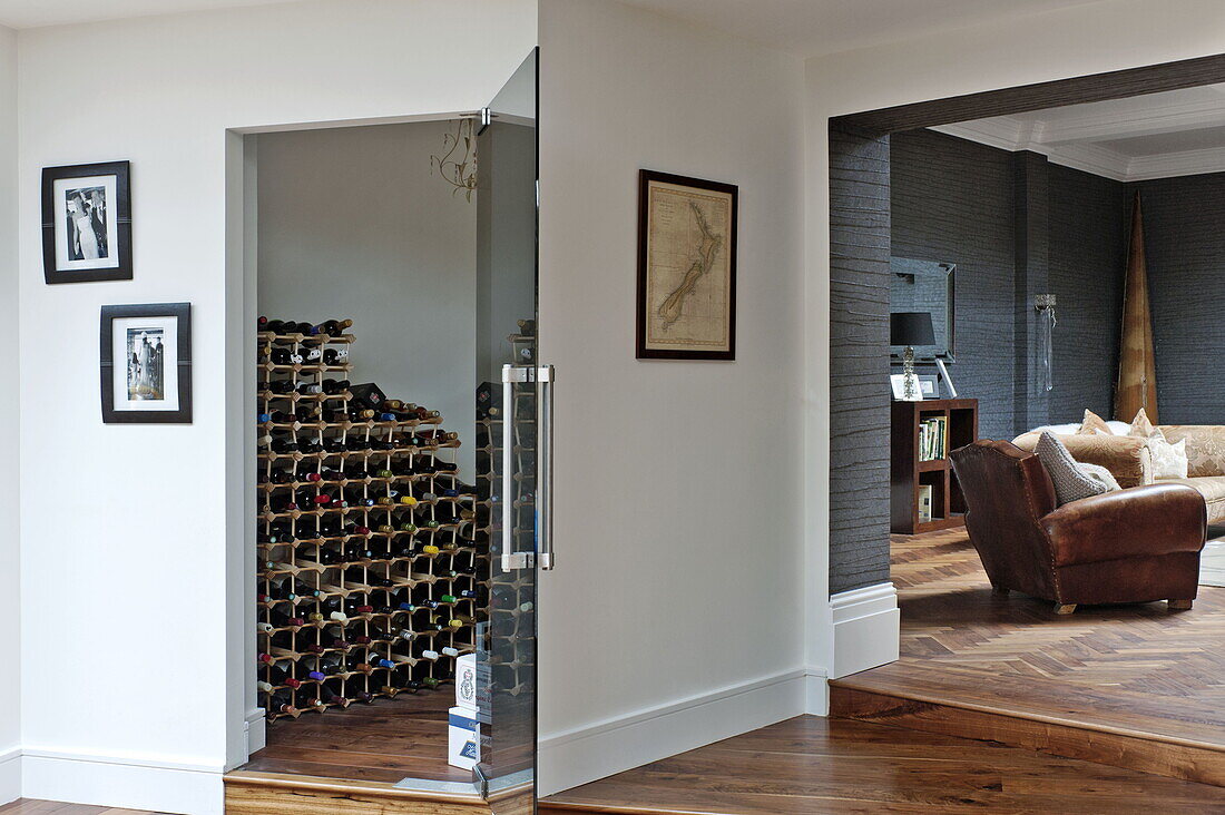 Weinflaschen im Lager und brauner Ledersessel im Wohnzimmer mit Parkettboden, Haus in London, England, UK