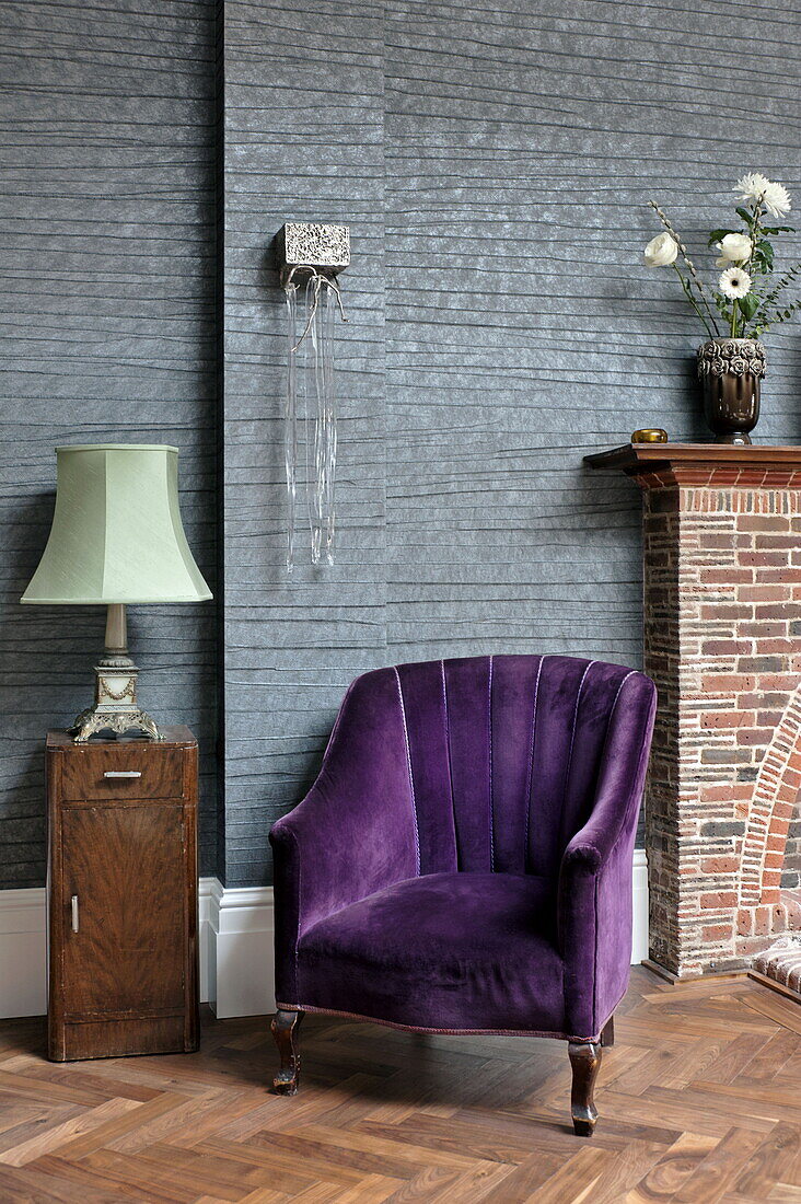Violetter Sessel mit Holzschrank und grüner Lampe im Wohnzimmer eines Hauses in London, England, UK