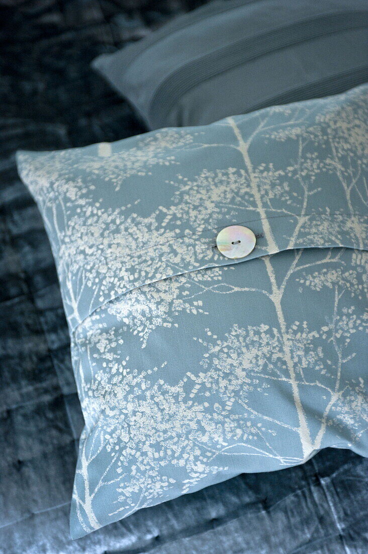 Light blue patterned cushion with mother of pearl button in London home, England, UK
