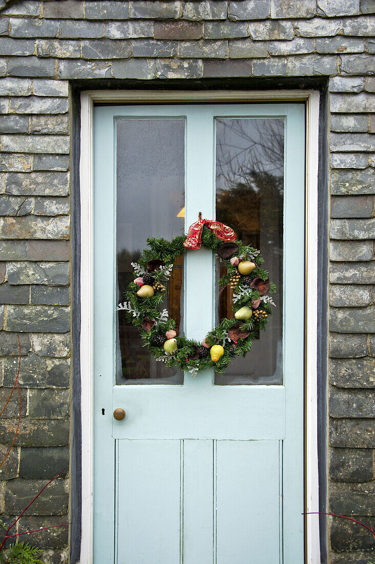 Weihnachtsgirlande an der Eingangstür eines Bauernhauses aus Stein, Cornwall, England, UK