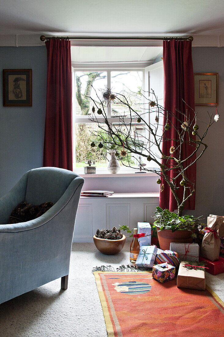 Christmas presents and blue armchair in living room of farmhouse, Cornwall, England, UK