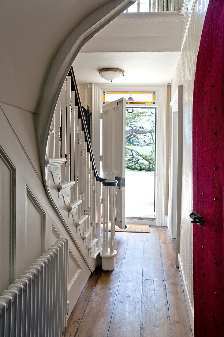 Entrance hallway and staircase with open front door in contemporary Suffolk country house, England, UK