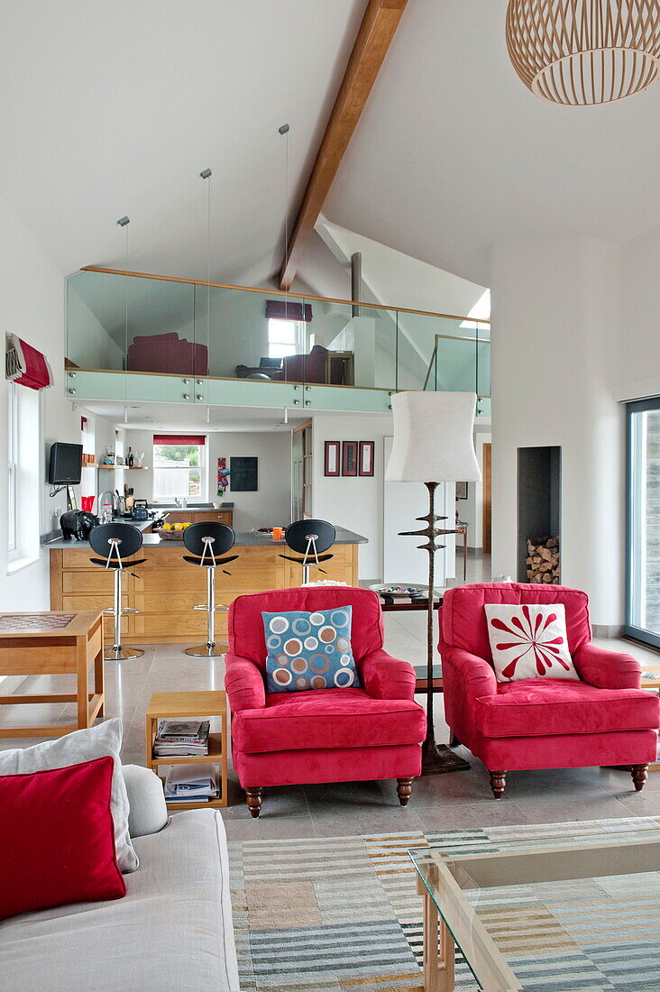 Passende Sessel in offenem, doppelhohem Wohnzimmer eines modernen Hauses, Cornwall, England, UK
