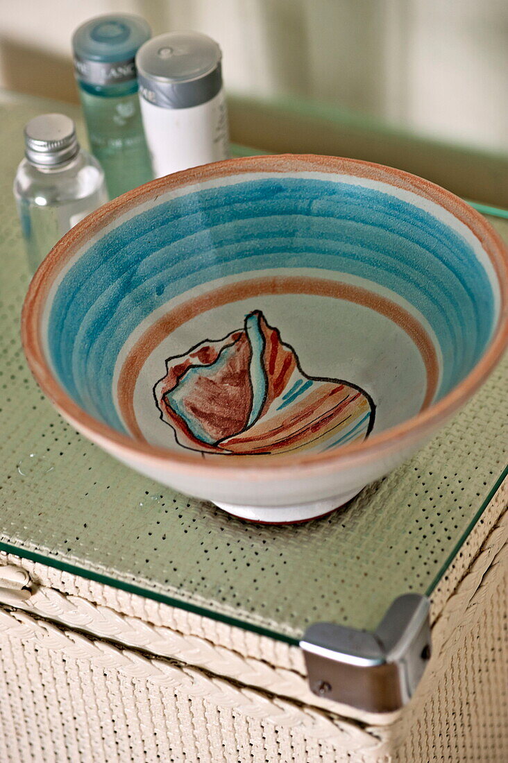 Hand painted bowl on wicker laundry box in Padstow bathroom, Cornwall, England, UK