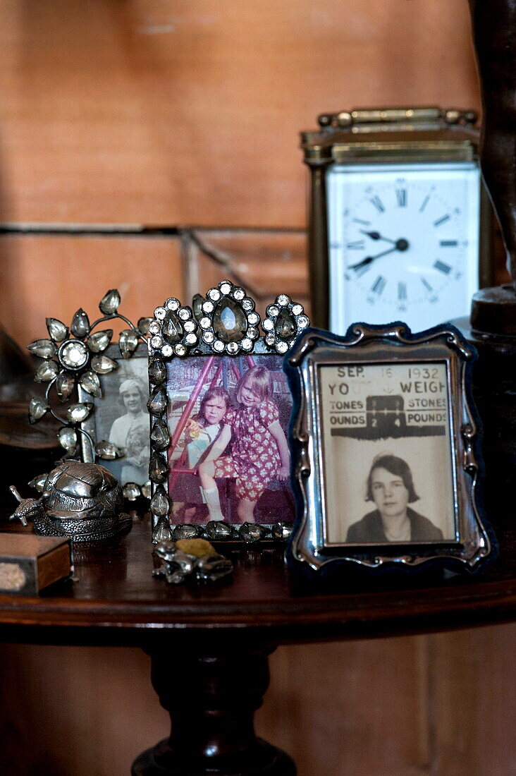 Family photographs and vintage clock on side table in London home, England, UK
