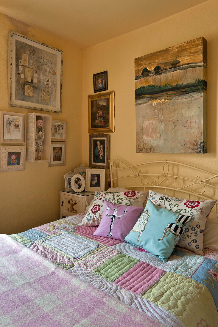Kissen und Kunstwerk mit Patchwork-Quilt im Schlafzimmer eines Hauses in London, England, UK