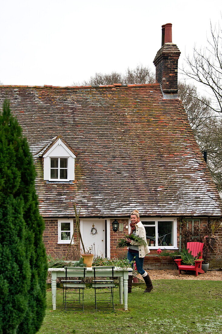 Frau geht im Garten eines Kachelhauses in Shropshire spazieren, England, Vereinigtes Königreich