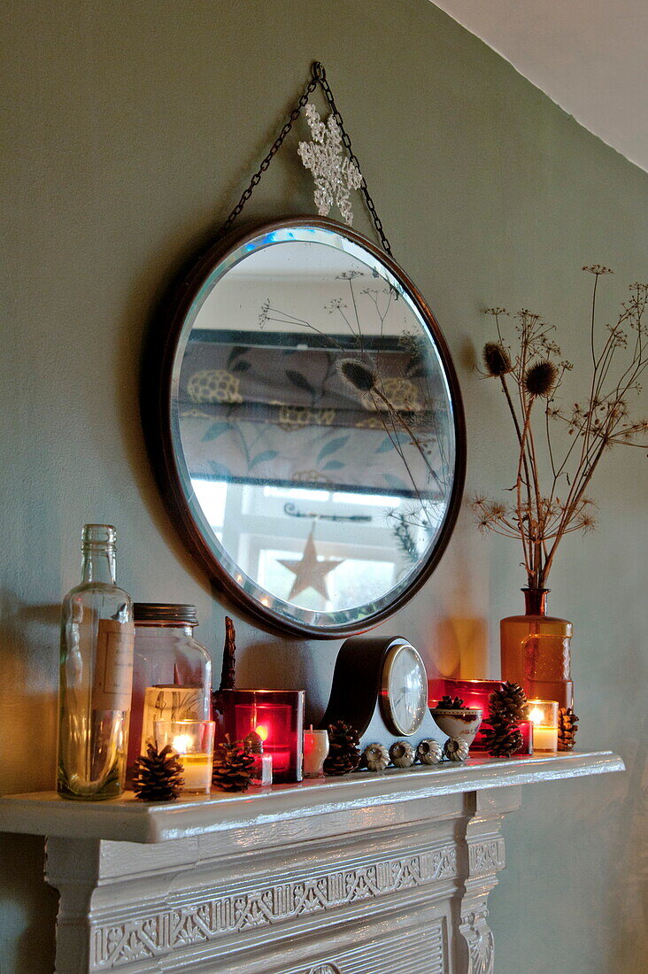 Vintage mirror with lit candles on mantlepiece in Shropshire cottage, England, UK