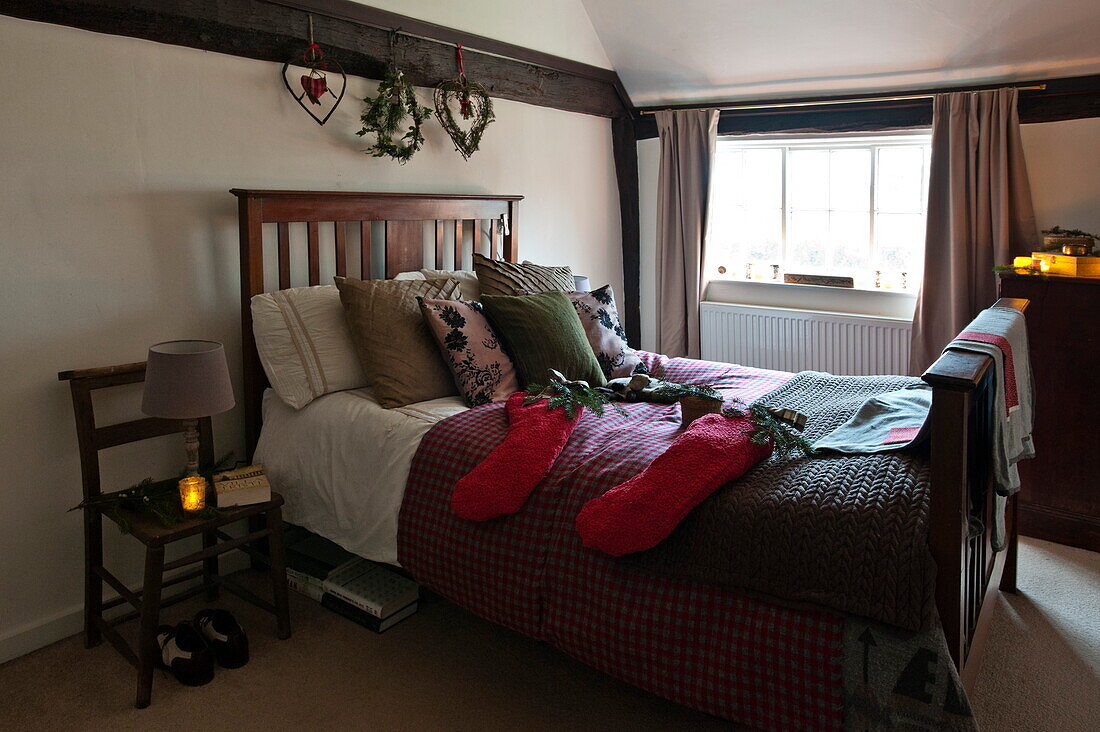 Christmas stockings on double bed with lit candle in Shropshire farmhouse, England, UK