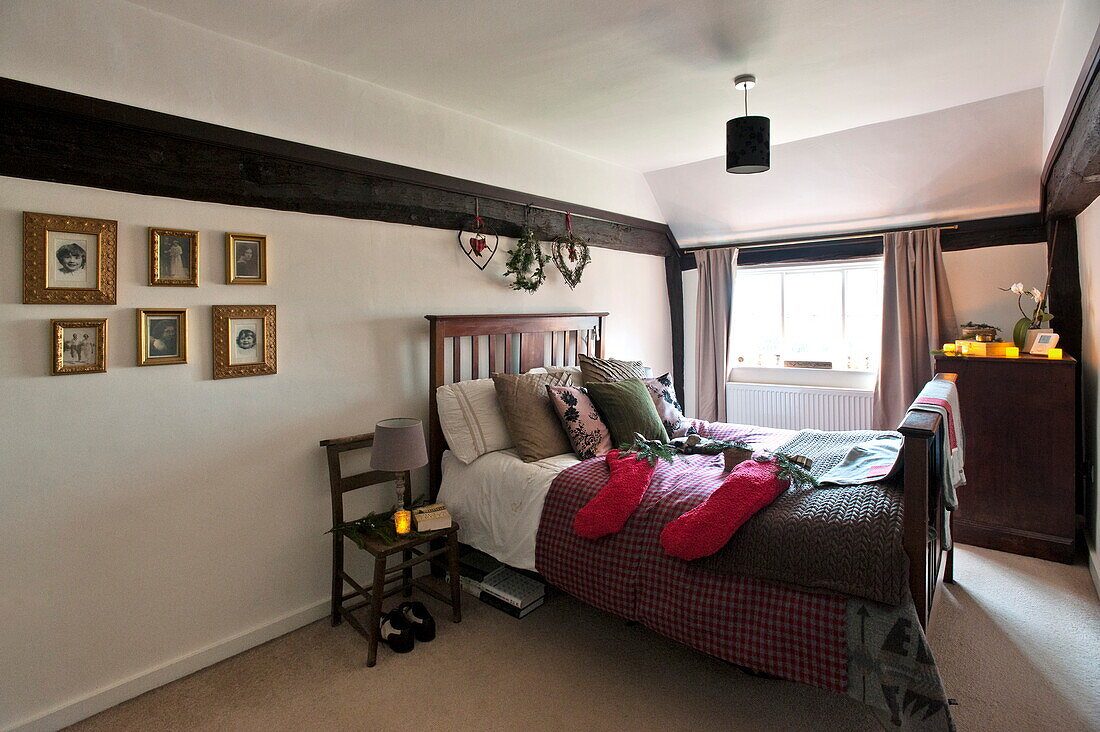 Christmas stockings on double bed with lit candle and artwork in Shropshire farmhouse, England, UK