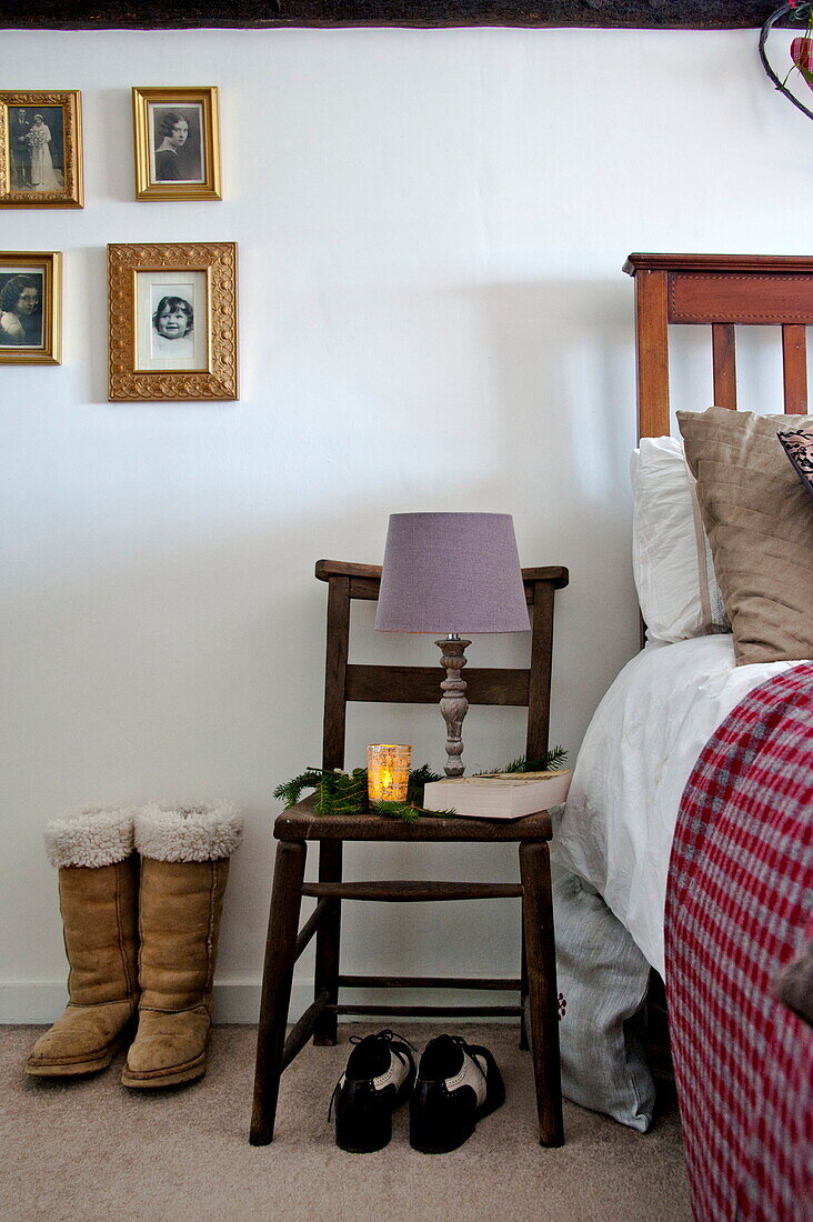 Purple lamp and family photographs with footwear at bedside in Shropshire cottage, England, UK