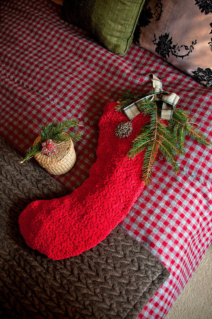 Christmas stocking on red and grey blanket in bedroom of Shropshire cottage, England, UK