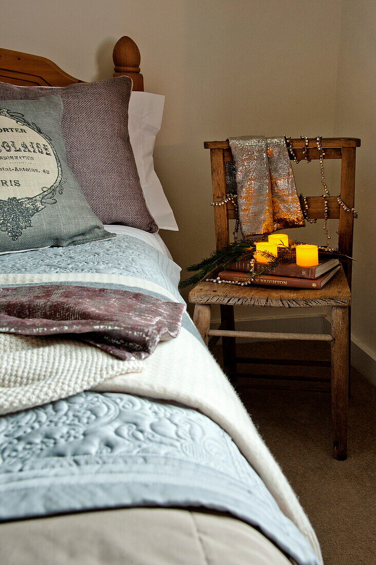 Beleuchtete Kerzen auf einem Stuhl am Bett in einem Landhaus in Shropshire, England, UK