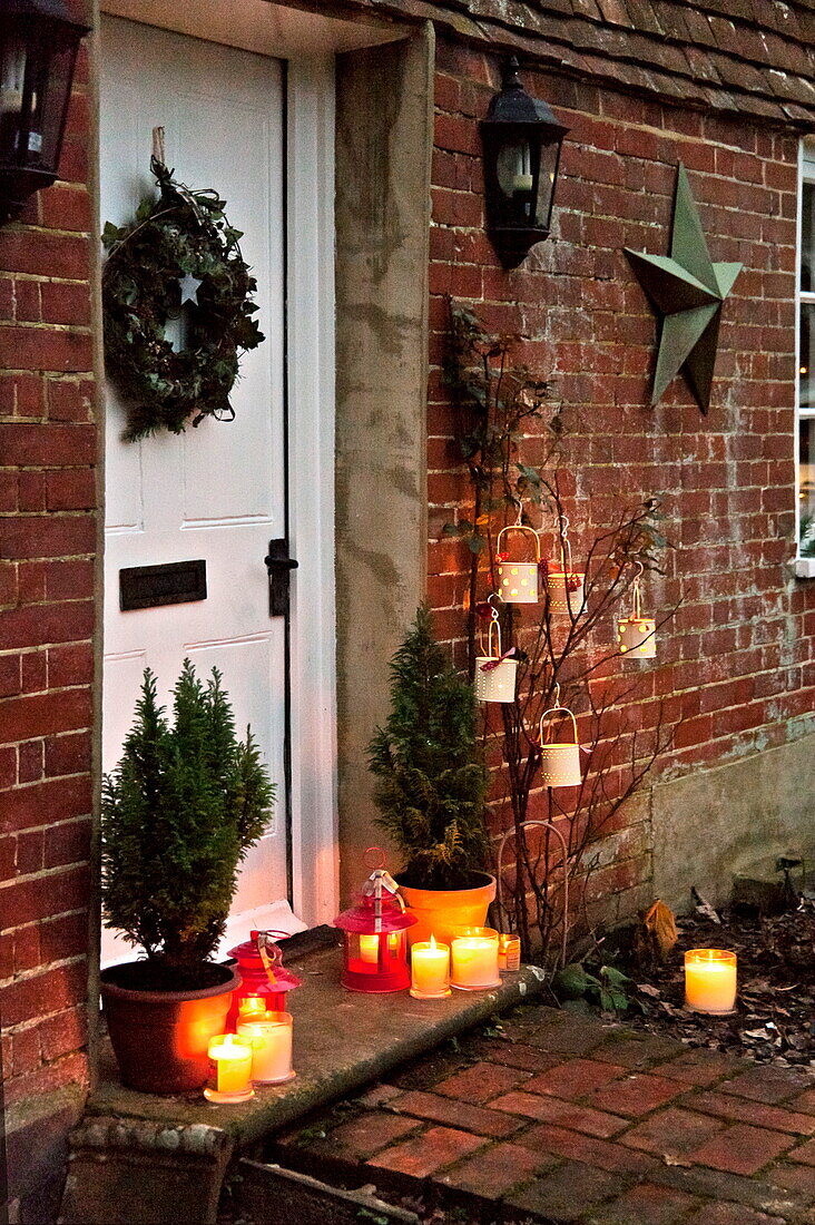 Lit candles on doorstep of brick Shropshire cottage, England, UK