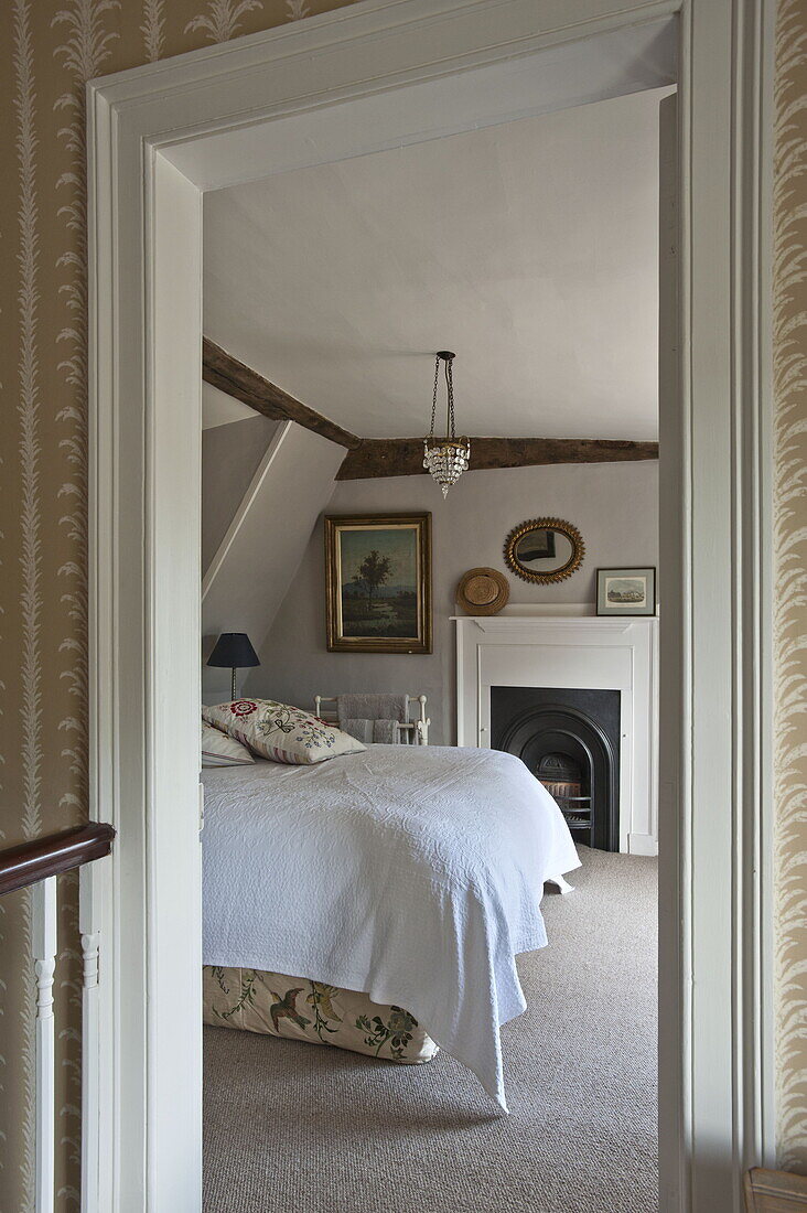 Blick durch die Tür auf bestickte Kissen auf dem Bett im Landhaus in Suffolk, England, UK