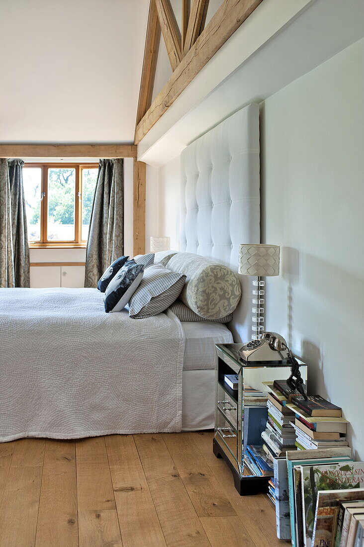 Doppelbett mit gepolstertem Kopfteil und verspiegeltem Nachttisch in einem modernen Haus in Suffolk/Essex, England, UK