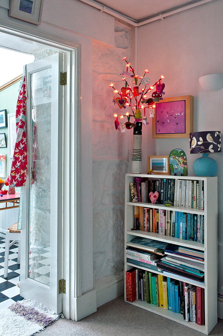 Bücherregal mit beleuchteter Dekoration in einem Cottage in Penzance, Cornwall, England UK
