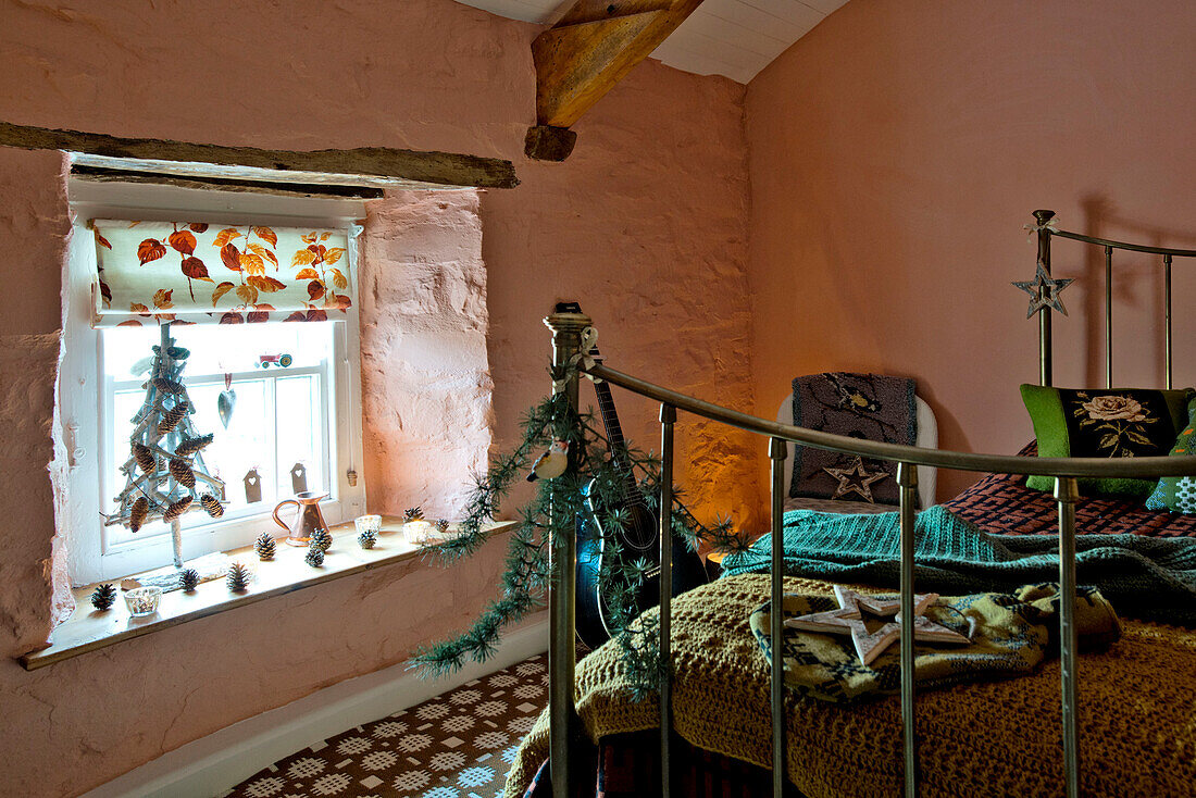 Trittbrett aus Messing mit Weihnachtsdekoration und Decken in einem pfirsichfarbenen Schlafzimmer in einem Haus in Tregaron, Wales, UK