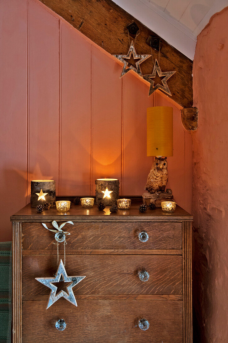 Wooden chest of drawers with star shaped decorations and candle holders in peach bedroom of Tregaron home Wales UK