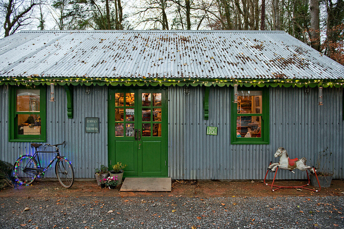 Bicycle with fairylights at exterior of corrugated metal shop with green paintwork in Tregaron Wales UK