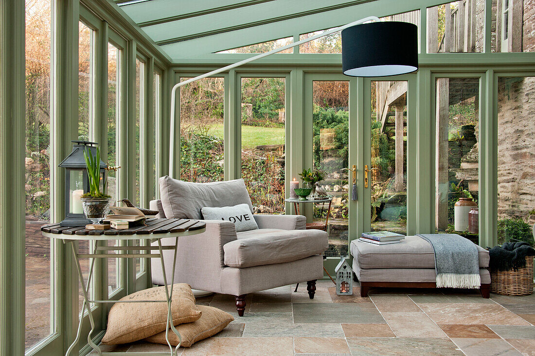 Armchair and footstool in garden conservatory of Sherford barn conversion Devon UK