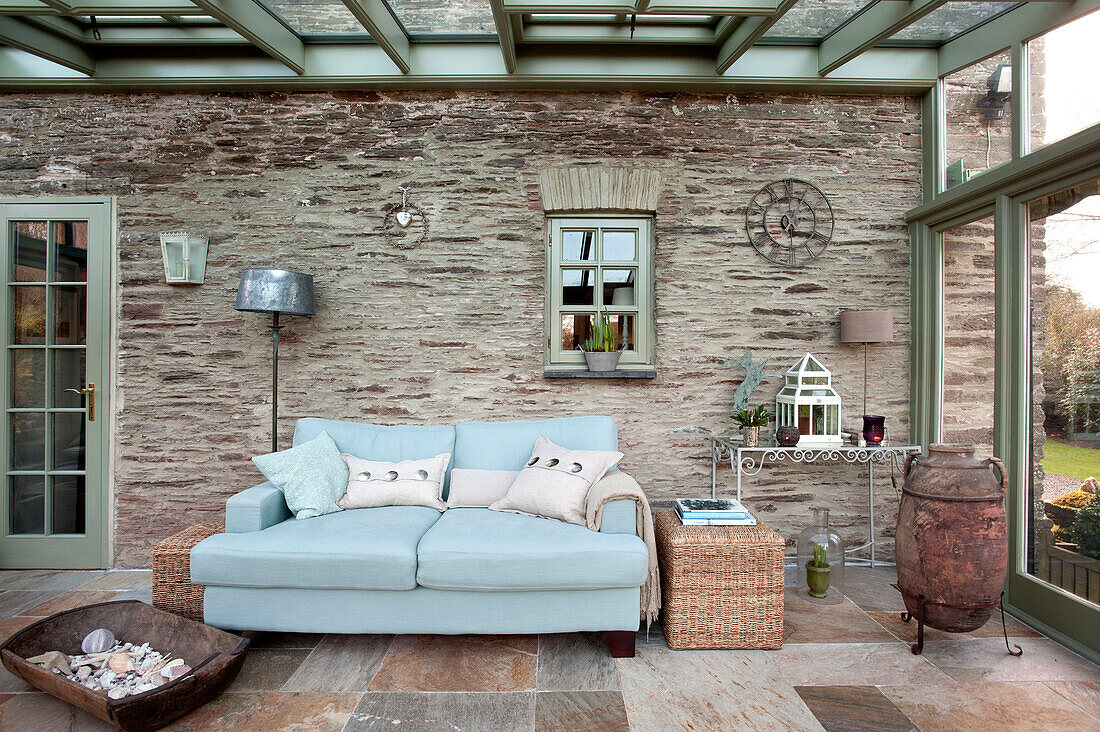 Light blue two seater sofa in stone conservatory of Sherford barn conversion Devon UK
