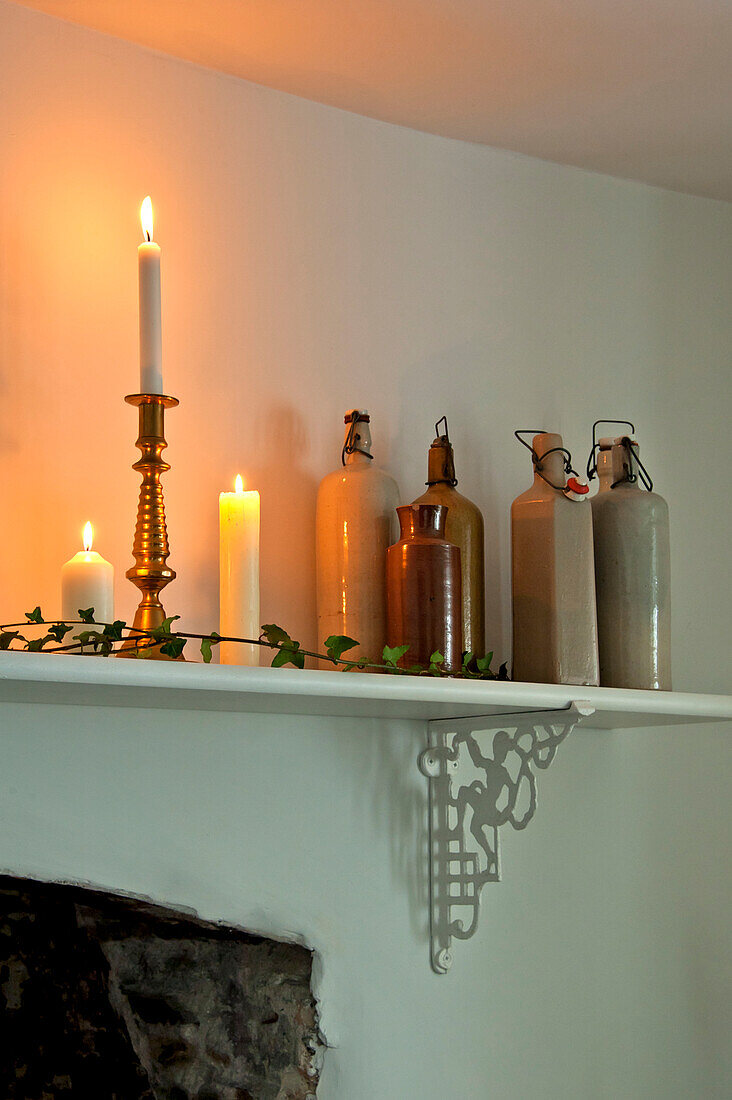 Beleuchtete Kerzen und Vorratsgläser auf dem Kaminsims in einem Haus in Crantock, Cornwall, England, UK