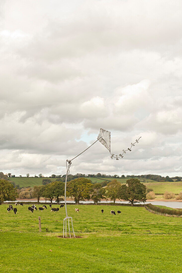 Metalldrachen-Skulptur auf einem Feld mit grasenden Kühen, Blagdon, Somerset, England, UK