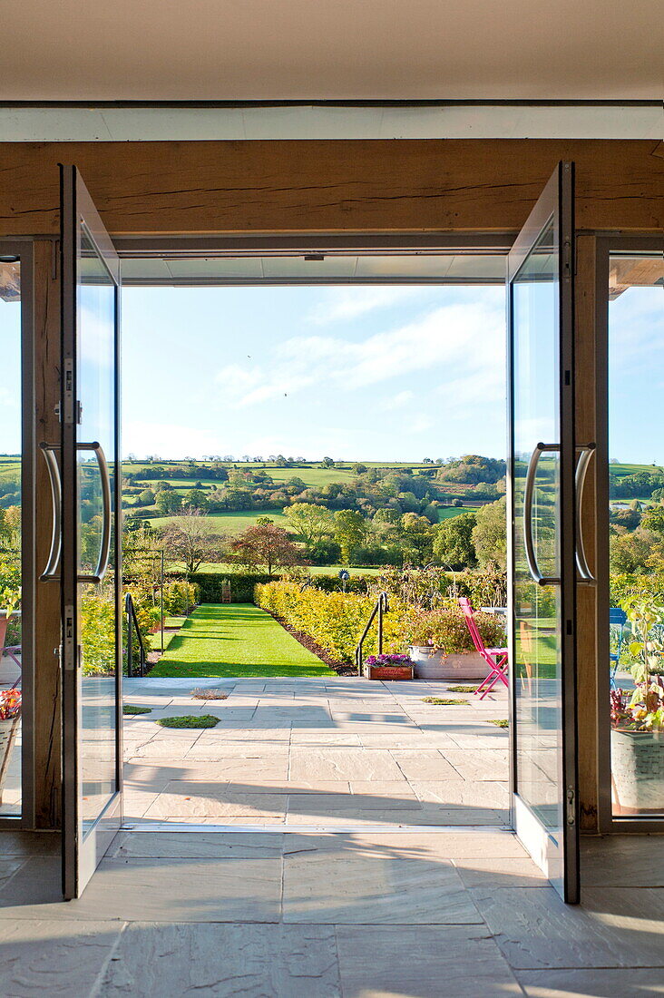Blick durch Flügeltüren in den Garten eines Landhauses in Blagdon, Somerset, England, UK