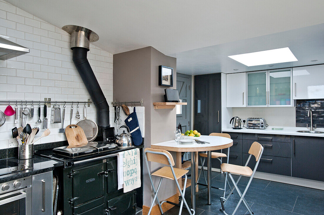 Klappstühle am Tisch mit Herd in der modernen Küche eines Hauses in Cornwall UK