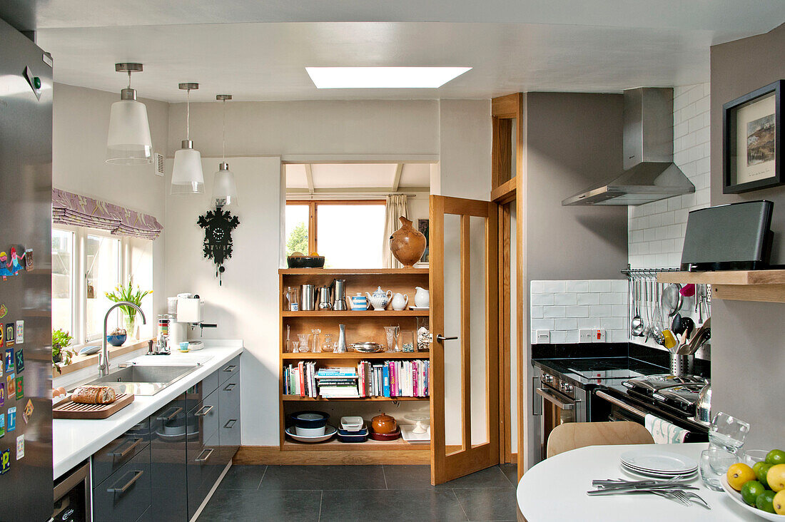 Open shelves with glass paned kitchen door in modern home, Cornwall, UK