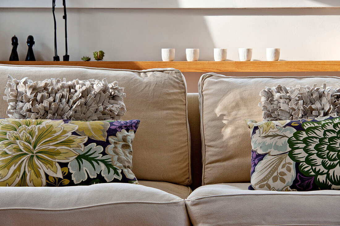Florale und strukturierte Kissen auf einem Zweisitzer-Sofa in einem Haus in Cornwall, UK