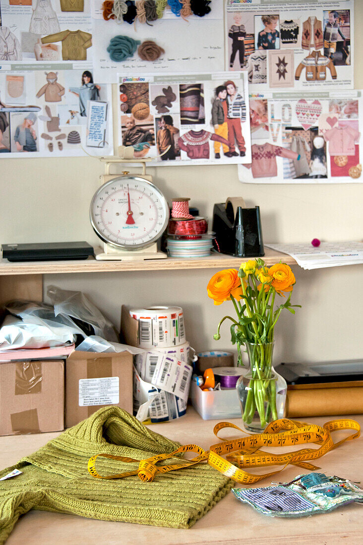 Waage und Schnittblumen mit Moodboards und Stoffen auf einer Werkbank im Studio in Cornwall, UK