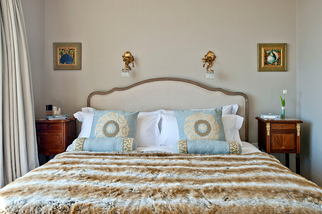 Light blue cushions on double bed with wooden cabinet in family home, Cornwall, UK