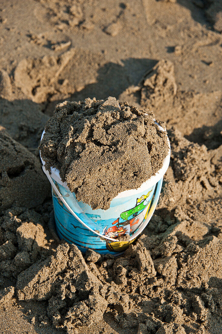 Bucket of sand on Cornwall beach UK