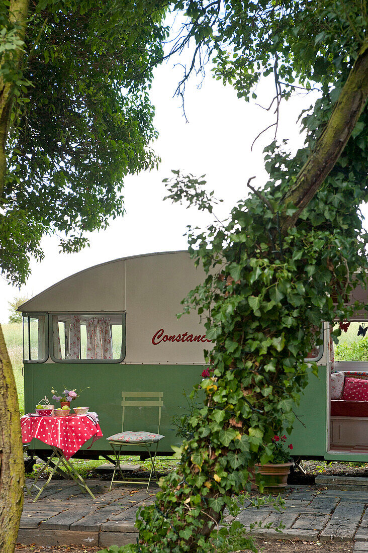 Klappstühle und Tisch auf einer schattigen Wohnwagen-Terrasse